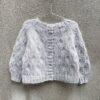 Olive Cardigan er en fin og anvendelig cardigan til børn i ren strukturstrik. Cardiganen strikkes frem og tilbage oppefra og ned og efter diagrammer. Der afsluttes med ribkanter på krop og ærmer, og til sidst samles masker op til knapstolpe, som ligeledes strikkes i rib. Størrelse: 9 (12) 18 måneder // (2) 4 (6) 8 (10) år Omkreds: ca. 57 (60) 63 // (67) 73 (76) 80 (84) cm Hel længde: ca. 28 (30) 32 // (35) 40 (43) 46 (49) cm Indvendig ærmelængde: ca. 19 (20) 22 // (23) 26 (32) 34 (37) cm Pinde: Rundpinde og strømpepinde 3 og 3,5 og 4 (4,5) 5 // (4) 5 (4) 4,5 (5) mm Strikkefasthed:  Pind 4 mm: 25 m x 30 rækker = 10 x 10 cm i mønster efter vask Pind 4,5 mm: 24 m x 28 rækker = 10 x 10 cm i mønster efter vask Pind 5 mm: 23 m x 26 rækker = 10 x 10 cm i mønster efter vask. Garn: 1 tråd Knitting for Olive Merino (250 m / 50 g) og  1 tråd Knitting for Olive Soft Silk Mohair (225 m / 25 g) Modellen på billedet er strikket i Merino - Perlegrå og Soft Silk Mohair - Pudderblå Garnforbrug:  Merino: 100 (100) 100 // (150) 150 (150) 200 (250) g Soft Silk Mohair: 50 (50) 75 // (75) 75 (100) 100 (125) g Knapper: 6 (6) 6 // (7) 7 (8) 8 (9) stk. 12 - 15 mm 